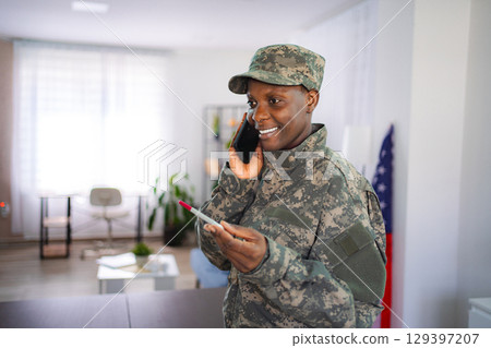 Smiling african american soldier talking on phone at home Smiling african american soldier talking on phone at home 129397207