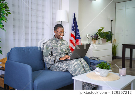 Smiling African American Female Soldier Using Laptop at Home 129397212