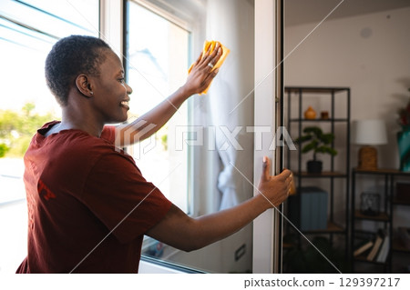 Young Woman Cleaning Windows in her Modern Apartment Young Woman Cleaning Windows in her Modern Apartment 129397217