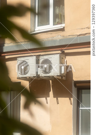 Air conditioners are installed on facade of building. device for comfortable living in hot weather. 129397360