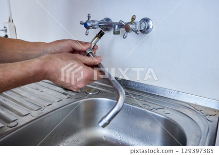 Removal of long spout from wall-mounted kitchen faucet, showing direct connection between faucet body and spout. Removal of long spout from wall-mounted kitchen faucet, showing direct connection between faucet body and spout. 129397385