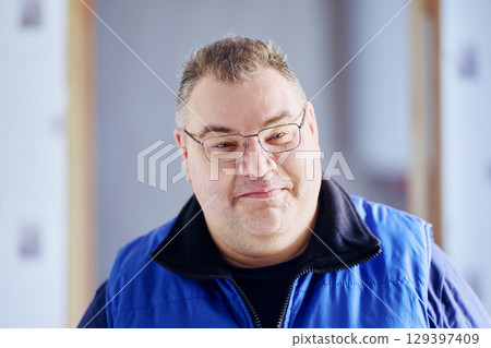 Grinning plump middle aged man of European appearance wearing glasses. 129397409