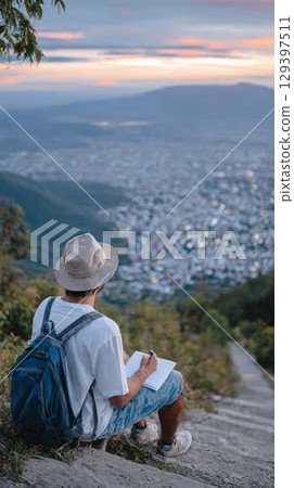 Solo traveler sits on mountain steps, sketching in notebook, surrounded by breathtaking landscape, embodying freedom and self-discovery in nature 129397511