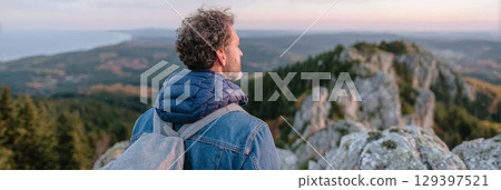 Solo traveler gazes at breathtaking mountain landscape, embracing freedom and adventure in a moment of self-discovery and inspiration 129397521