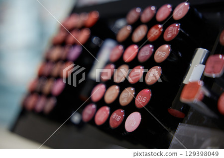 A row of lipsticks is displayed in a cosmetics store A row of lipsticks is displayed in a cosmetics store 129398049