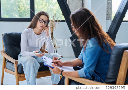 Sad teenage girl student talking with social psychologist, therapist, counselor Sad teenage girl student talking with social psychologist, therapist, counselor 129398295