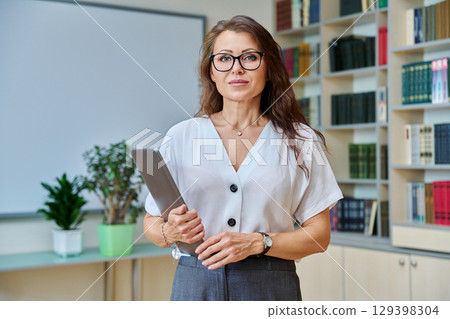 Portrait confident mature woman teacher, educational counsellor in classroom Portrait confident mature woman teacher, educational counsellor in classroom 129398304