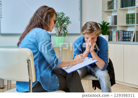 Sad teenage boy in mental therapy session, talking with school counsellor Sad teenage boy in mental therapy session, talking with school counsellor 129398311