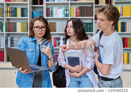 Two teenage students meeting talking with female teacher in library 129398320