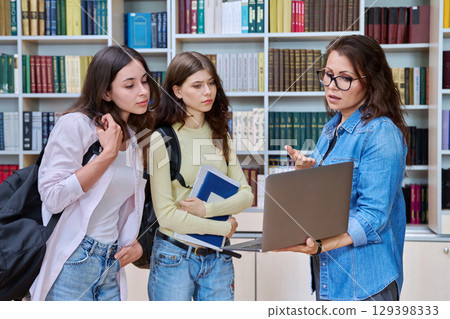 Teenage students girls meeting discussing with teacher mentor in classroom 129398333