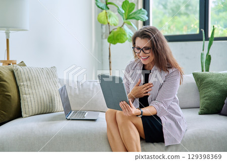Middle aged woman working remotely, video conference, using digital tablet 129398369