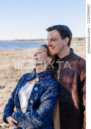 Portrait loving couple walks on beach along sea on sunny autumn day. Weekend and lifestyle concept. Vertical photo. High quality photo 129398462