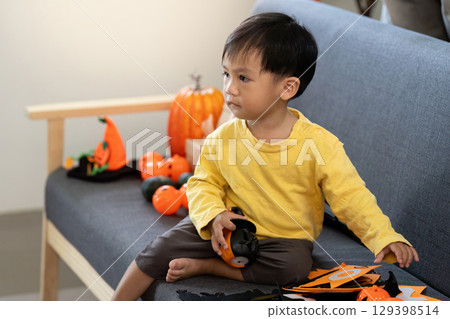 Halloween Fun. Young child playing with festive decorations at home. 129398514