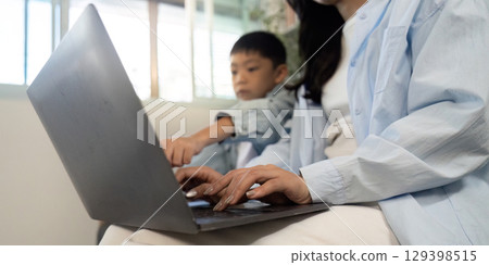 Learning Together. Mother and son collaborating on a laptop. 129398515