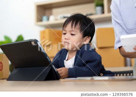 Focused Child Engaged with Tablet in Home Office Focused Child Engaged with Tablet in Home Office 129398576