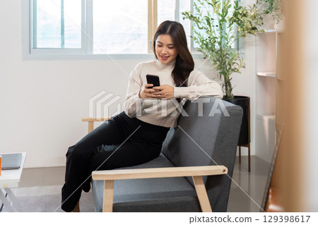 Engaged woman texting on smartphone while relaxing at home 129398617