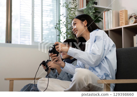 Gaming Together. Mother and son enjoying video games on a couch. 129398660