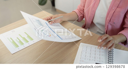 Remote Work: Professional woman analyzing data and reports at home office 129398678