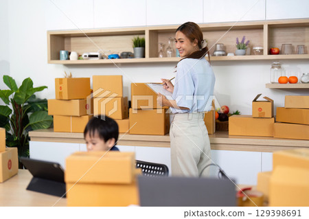 Mom taking notes while son engages with technology Mom taking notes while son engages with technology 129398691