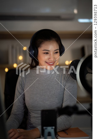 Podcast session. Woman smiling while engaging with audience during a podcast recording. Podcast session. Woman smiling while engaging with audience during a podcast recording. 129398713