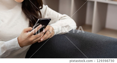 Engaged Interaction. Young woman using smartphone while relaxing at home. Engaged Interaction. Young woman using smartphone while relaxing at home. 129398730