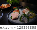 Detailed view of salmon and tuna sashimi artfully arranged on a green leaf with garnish. 129398868
