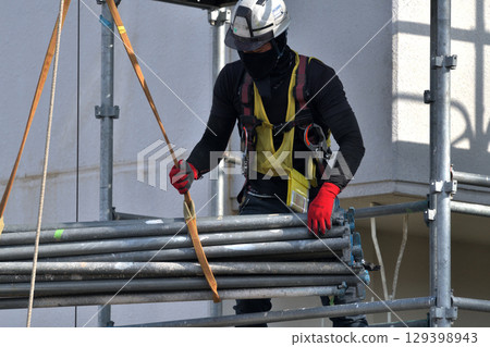 Large-scale repair work on an apartment building - Scaffolding workers assembling temporary scaffolding 129398943