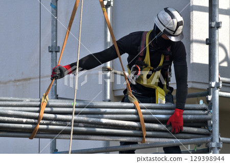 Large-scale repair work on an apartment building - Scaffolding workers assembling temporary scaffolding 129398944