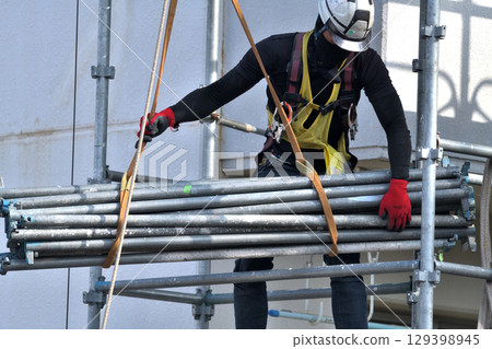 Large-scale repair work on an apartment building - Scaffolding workers assembling temporary scaffolding 129398945