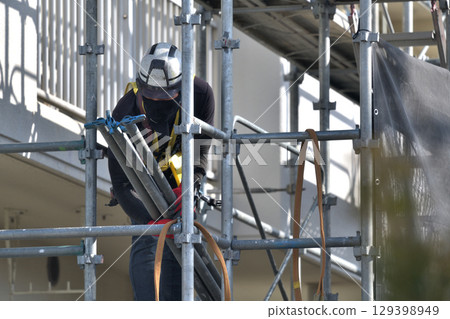 Large-scale repair work on an apartment building - Scaffolding workers assembling temporary scaffolding 129398949