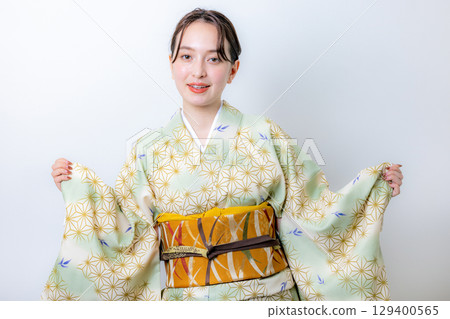 一個穿著和服的女人拿著一朵花 129400565