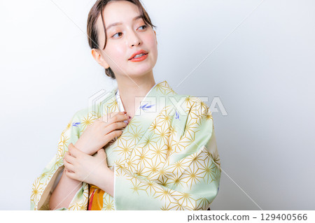 一個穿著和服的女人拿著一朵花 129400566