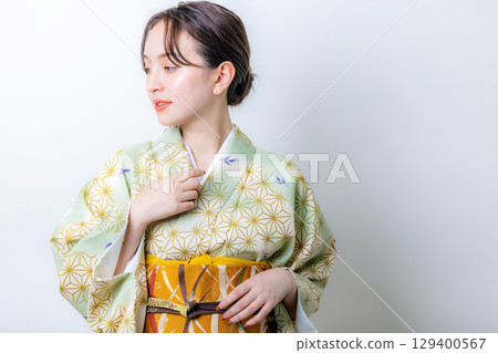 一個穿著和服的女人拿著一朵花 129400567