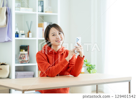 A young woman using a smartphone in the living room A young woman using a smartphone in the living room 129401542