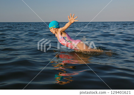 Girl swimmer 8 years old jumps out of sea and swimming in sunny day 129401621