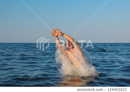 Man jumps out of sea in sunny day 129401622