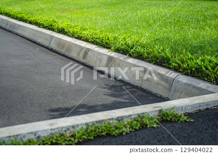 Lush green grass along the curb and road 129404022