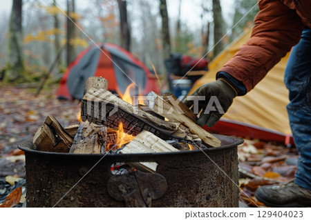 Campers preparing a bonfire and a tent in the forest 129404023