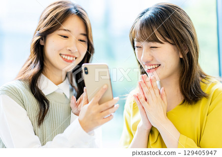 兩名年輕女子帶著智慧型手機 兩名年輕女子帶著智慧型手機 129405947