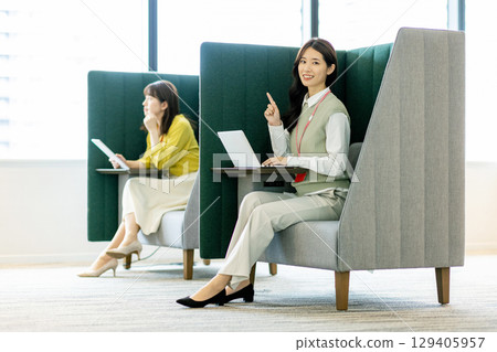 Business woman in a suit teleworking in an office booth Business woman in a suit teleworking in an office booth 129405957