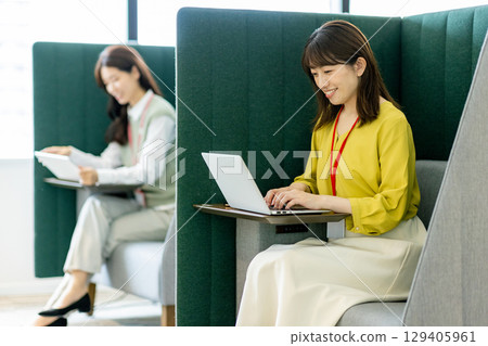 Business woman in a suit teleworking in an office booth Business woman in a suit teleworking in an office booth 129405961