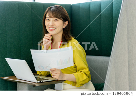 Business woman in a suit teleworking in an office booth Business woman in a suit teleworking in an office booth 129405964