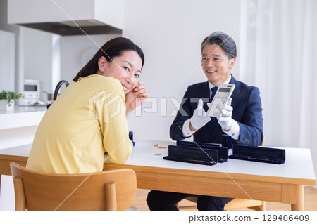 On-site purchase: A housewife having her items appraised at home 129406409