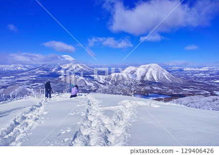 Skiers looking at Mount Yotei from off-piste in the East Area at Rusutsu Ski Resort in Hokkaido, Japan, on a clear winter day Skiers looking at Mount Yotei from off-piste in the East Area at Rusutsu Ski Resort in Hokkaido, Japan, on a clear winter day 129406426