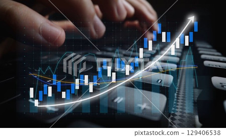 Close-up of hands typing on a keyboard while analyzing stock market trends represented by a digital graph with upward motion and various data points Copula 129406538