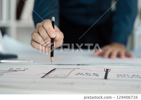 Engineer analyzing architectural blueprint in modern office environment for effective design solutions 129406716