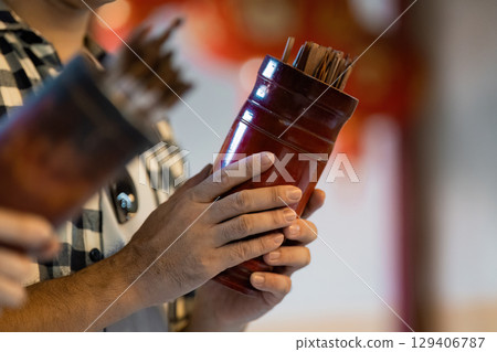 Cultural travel exploration traditional fortune sticks ceremony local temple event indoor setting close-up view spirituality Cultural travel exploration traditional fortune sticks ceremony local temple event indoor setting close-up view spirituality 129406787