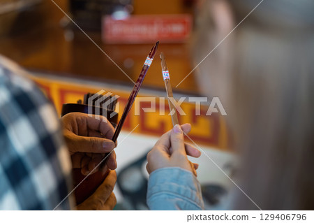 Cultural travel experience artisans crafting traditional brushes local market close-up view artistic environment unique perspective 129406796