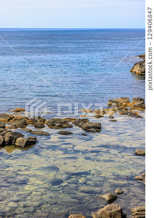 北海道黃金岬。一個寧靜的夏日午後,多雲的天空下,海浪拍打著海岸。 北海道黃金岬。一個寧靜的夏日午後,多雲的天空下,海浪拍打著海岸。 129406847
