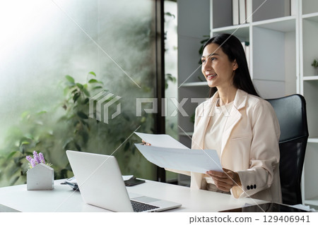 Professional woman reviewing documents in modern office indoor workspace business environment bright natural light motivational concept Professional woman reviewing documents in modern office indoor workspace business environment bright natural light motivational concept 129406941